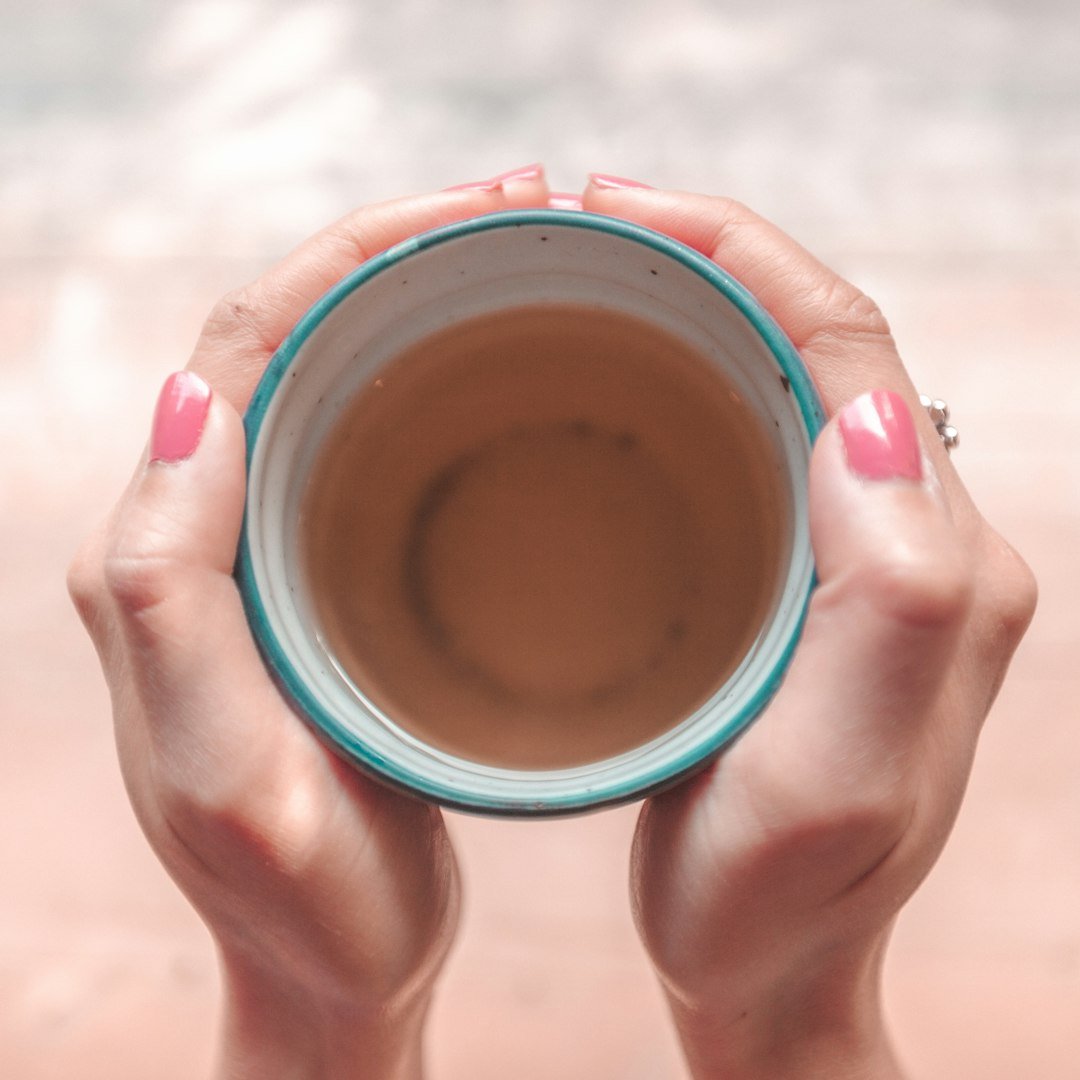 Person holding a blue ceramic mug in both hands