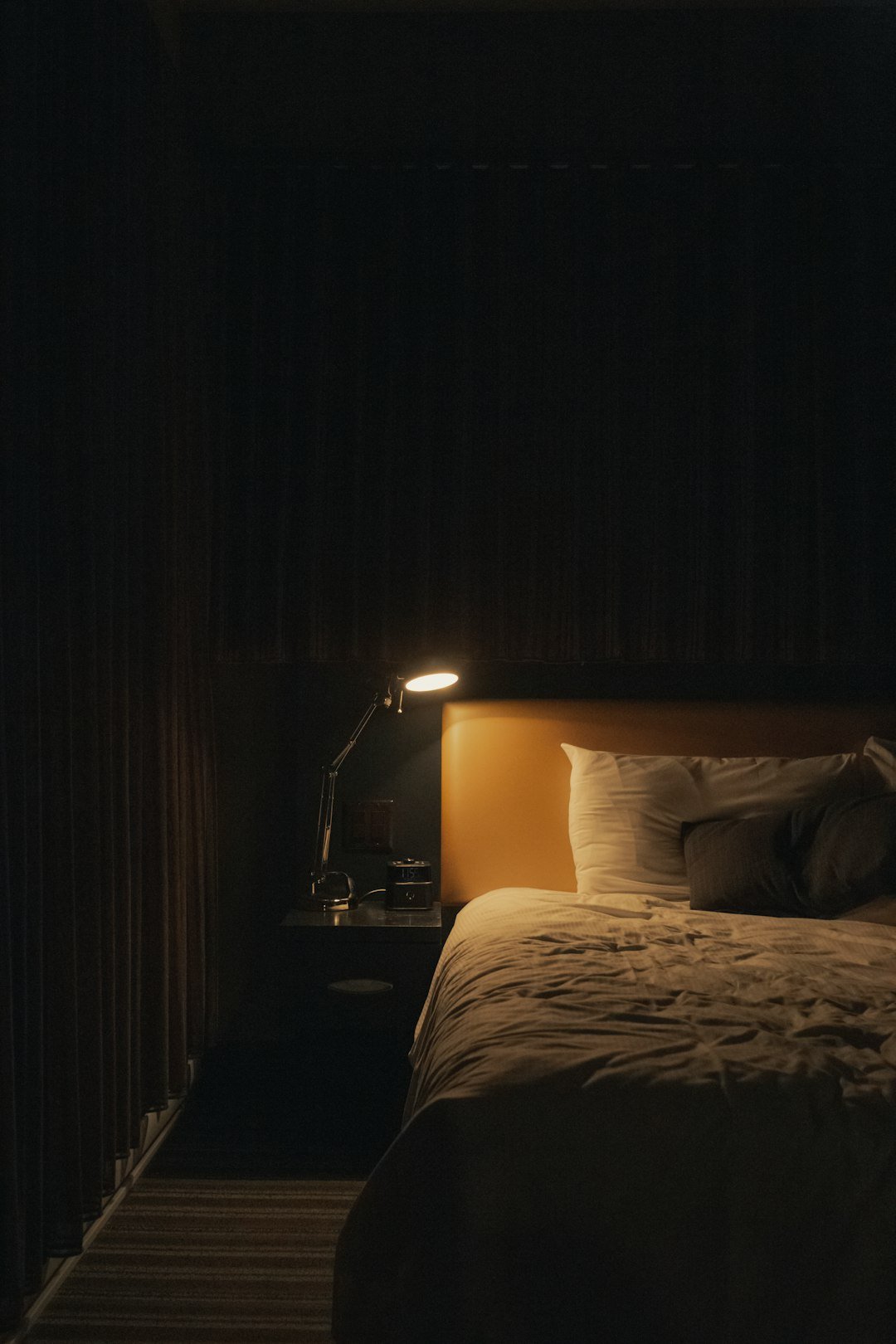 Softly lit lamp beside a bed in a quiet bedroom at night